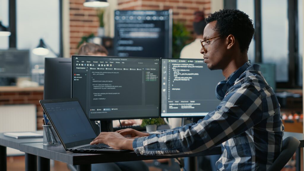 Photo of a person on a laptop with coding screenshots in the background